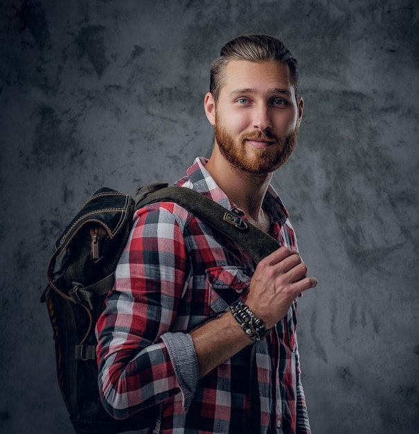 Foto gratuita el elegante viajero urbano pelirrojo sostiene una mochila sobre fondo gris en un estudio.