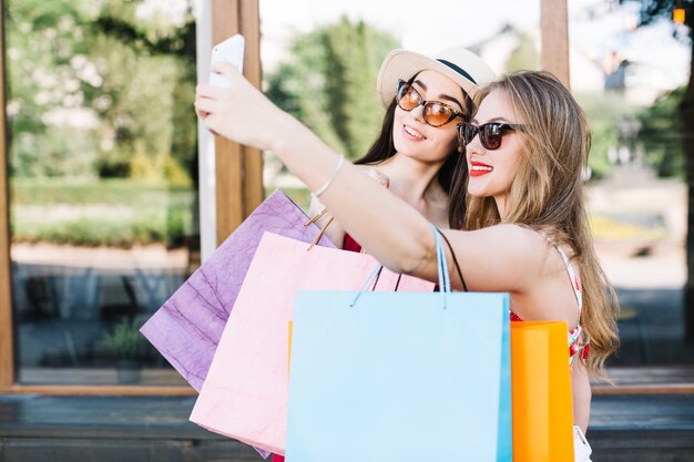 Elegantes amigos tomando selfie después de ir de compras