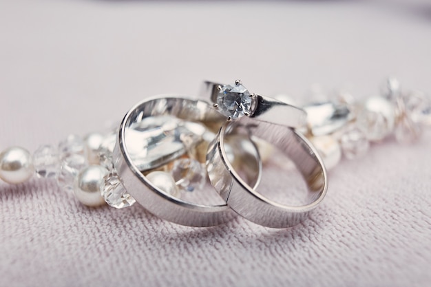Elegantes anillos de boda de plata hechos de oro blanco se encuentran en la pulsera de cristal.
