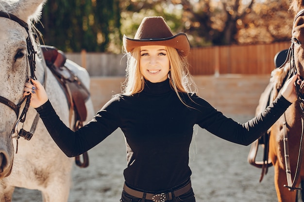 Elegantes chica con un caballo en un rancho.