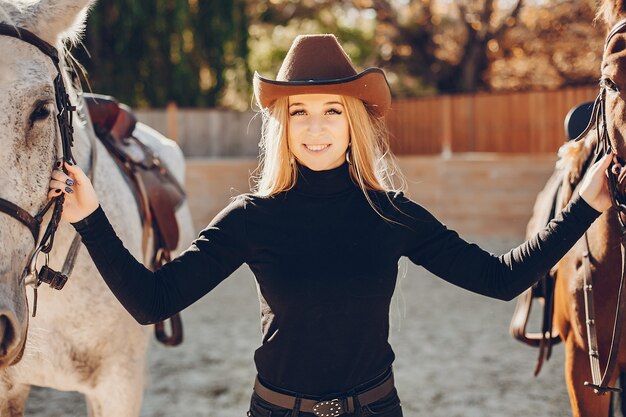 Elegantes chica con un caballo en un rancho.