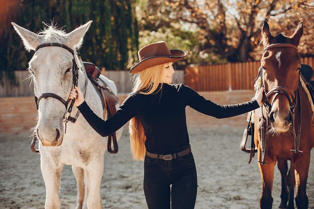 Elegantes chica con un caballo en un rancho.