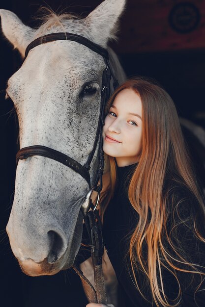 Elegantes chica con un caballo en un rancho.