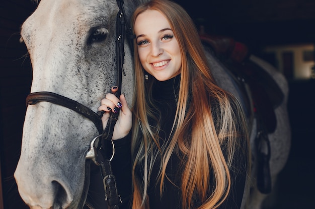 Elegantes chica con un caballo en un rancho.
