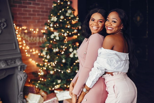 Elegantes chicas negras en las decoraciones navideñas