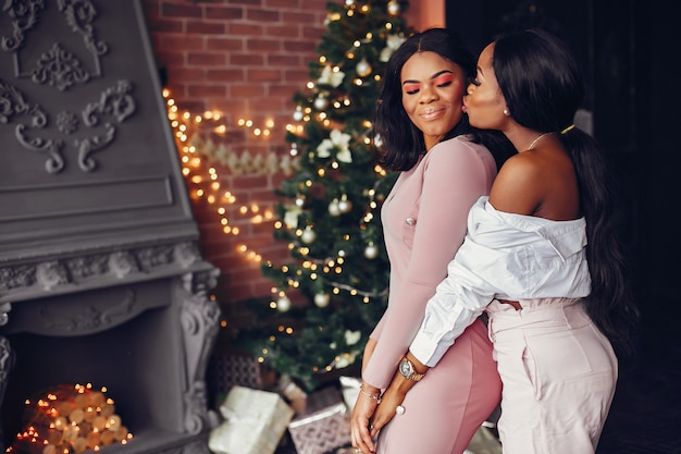 Elegantes chicas negras en las decoraciones navideñas