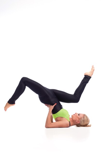 Ella tiene su equilibrio. Foto de estudio vertical de una gimnasta en forma haciendo un soporte de hombro con las piernas levantadas en el aire copyspace arriba aislado