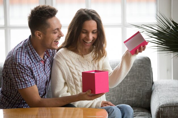 Emocionada apertura de caja de regalo de apertura de mujer joven presente de marido