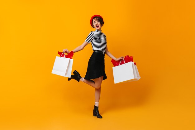 Emocionada dama morena bailando con bolsas de tienda