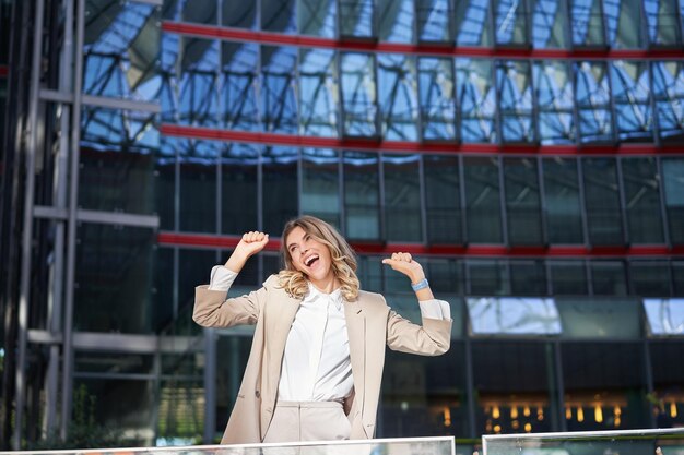 Emocionada joven empresaria celebrando triunfar sintiéndose libre y feliz posando en la ciudad cerca de