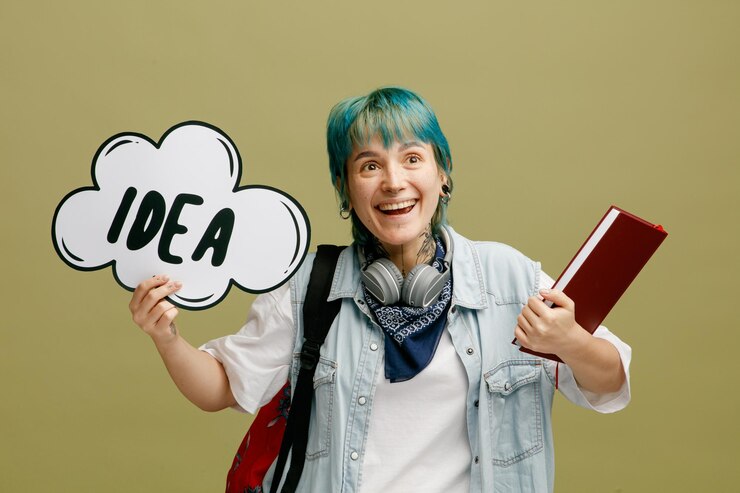 Foto gratuito emocionada joven estudiante con auriculares y pañuelo en el cuello y mochila sosteniendo un cuaderno mirando hacia arriba mostrando una burbuja de ideas aislada en un fondo verde oliva