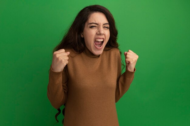 Emocionada joven hermosa mostrando sí gesto aislado en la pared verde