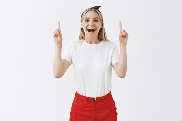 Emocionada joven rubia alegre posando contra la pared blanca