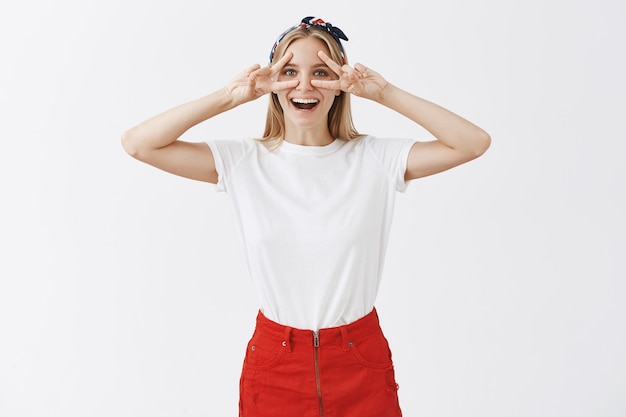 Emocionada joven rubia alegre posando contra la pared blanca