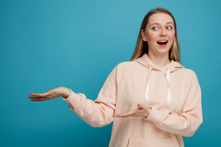 Foto gratuito emocionada joven rubia apuntando al lado con las manos