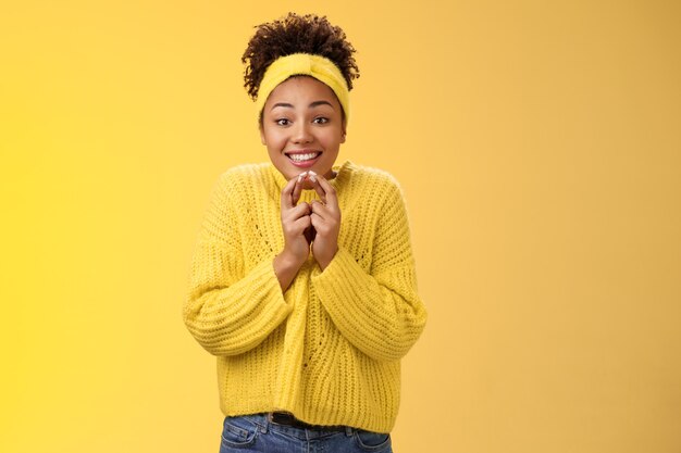 Emocionada linda encantadora niña sonriente afroamericana cruzar los dedos buena suerte presionar las manos juntas sonriendo mirar con suerte cámara rezando buena suerte sueño hecho realidad creer recibir noticias positivas.