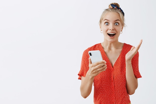 Foto gratuita emocionada y sorprendida joven rubia posando contra la pared blanca