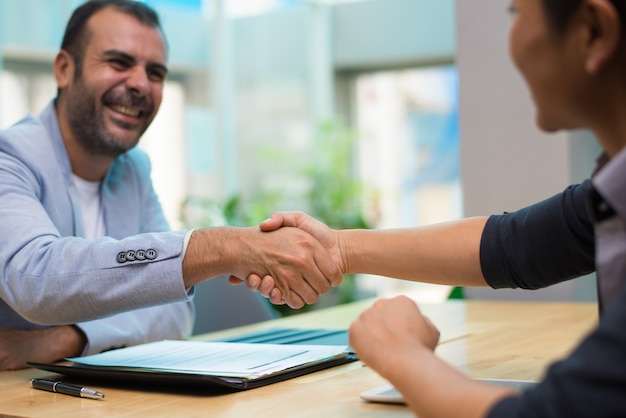 Foto gratuita emocionado empleador hispano felicitando a nuevo empleado.