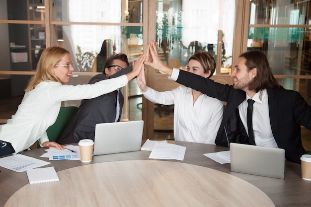 Foto gratuita emocionado equipo de trabajo dando alta cinco celebrando logros compartidos