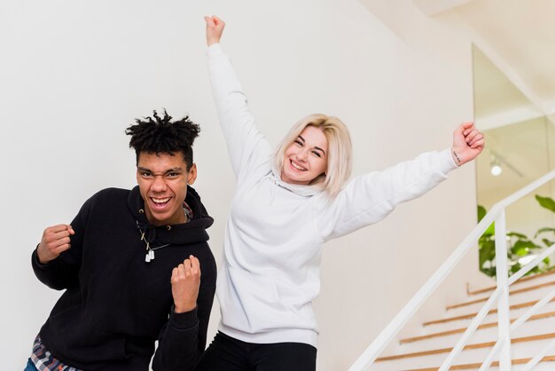 Emocionado feliz pareja adolescente interracial mirando a cámara