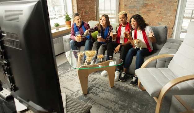 Emocionado grupo de personas viendo el campeonato de partidos deportivos en casa