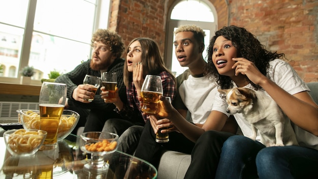 Emocionado grupo de personas viendo el campeonato de partidos deportivos en casa