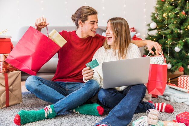 Emocionado hombre y mujer con compras y portátil