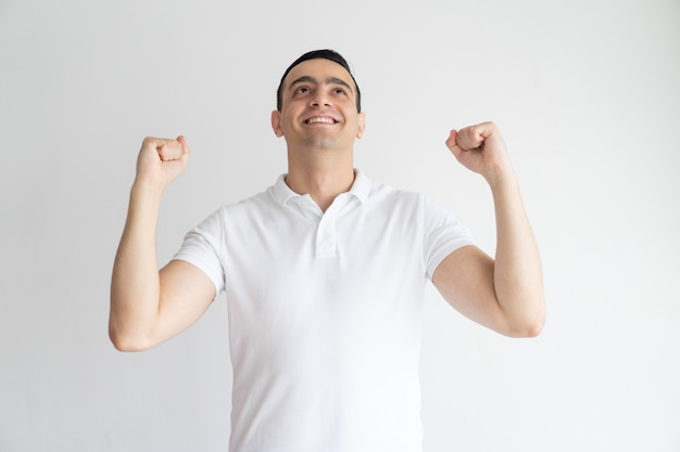 Emocionado joven guapo celebrando el éxito y haciendo sí gesto.