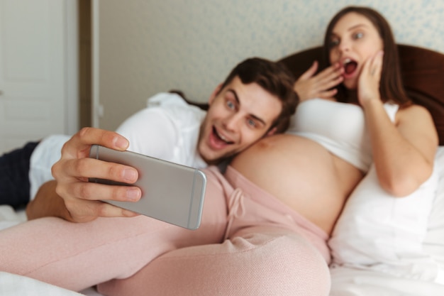 Emocionado joven pareja embarazada tomando selfie