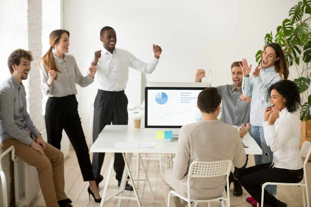 Emocionados por las buenas noticias, colegas motivados que celebran juntos el éxito corporativo.