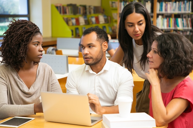 Emocionados colegas discutiendo algunas preguntas en la biblioteca