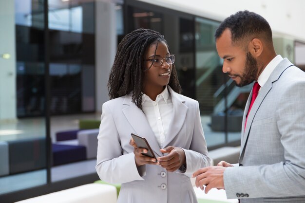 Emocionados colegas de negocios que miran contenido en el teléfono móvil