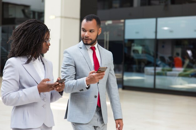 Emocionados colegas de negocios que usan teléfonos móviles