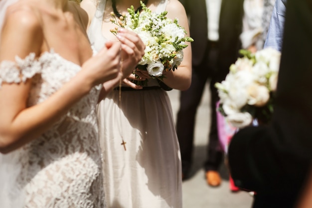 Emocional morena hermosa novia en vestido de cosecha blanca poniendo en crucifijo