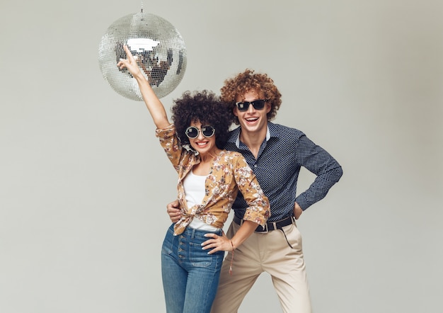 Emocional sonriente retro amorosa pareja bailando cerca de la bola de discoteca.