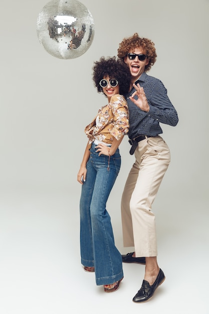 Foto gratuita emocional sonriente retro amorosa pareja bailando cerca de la bola de discoteca.