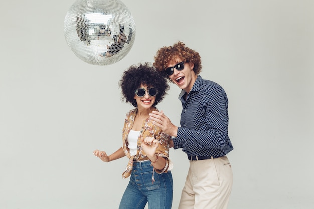 Emocional sonriente retro amorosa pareja bailando cerca de la bola de discoteca.