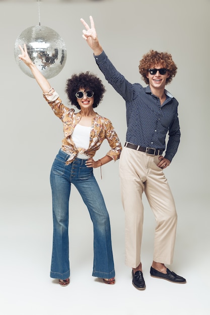 Foto gratuita emocional sonriente retro amorosa pareja bailando cerca de la bola de discoteca.