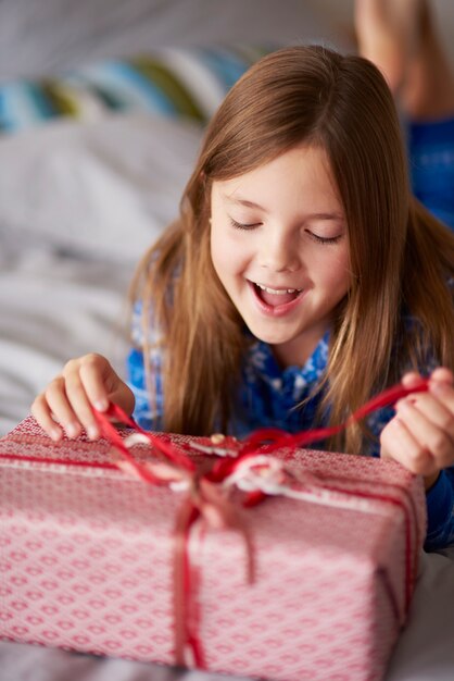 Emocionante niña abriendo regalo de Navidad