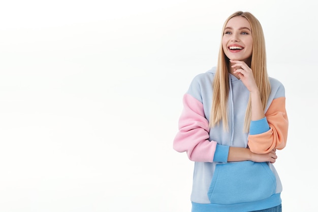 Emociones, mujeres y concepto de belleza. Retrato de niña rubia alegre riendo mientras mira a la izquierda con una sonrisa complacida y satisfecha