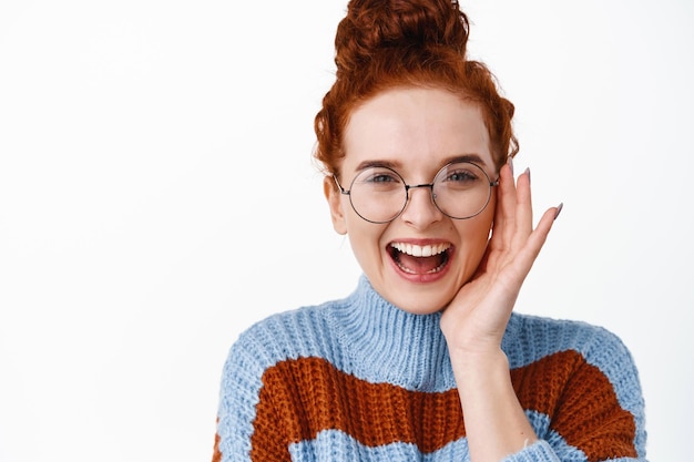 Emociones positivas. Chica pelirroja feliz en vasos riendo sin preocupaciones. Mujer con cabello pelirrojo y gafas tocando su rostro, sonriendo en blanco