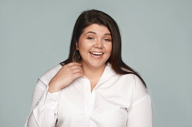 Emociones, sentimientos y reacciones positivas. Hermosa empleada joven encantadora con cabello oscuro suelto riéndose de broma posando