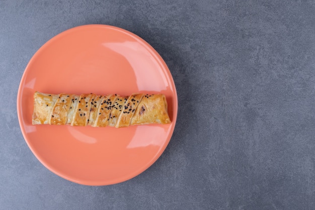 Empanada de sésamo en placa sobre mesa de mármol.