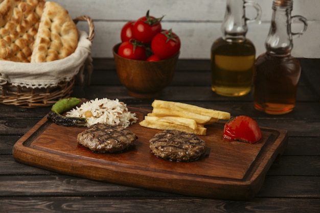 Foto gratuita empanadas de carne a la parrilla servidas con arroz, papas fritas, tomate a la parrilla y pimienta