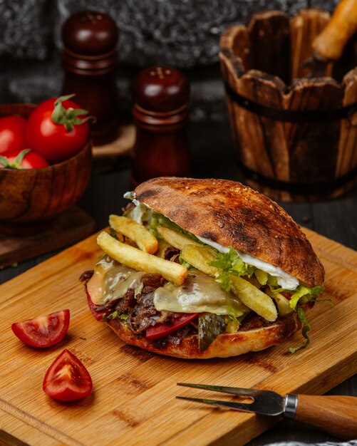 Emparedado de pan con carne, papas fritas y verduras.