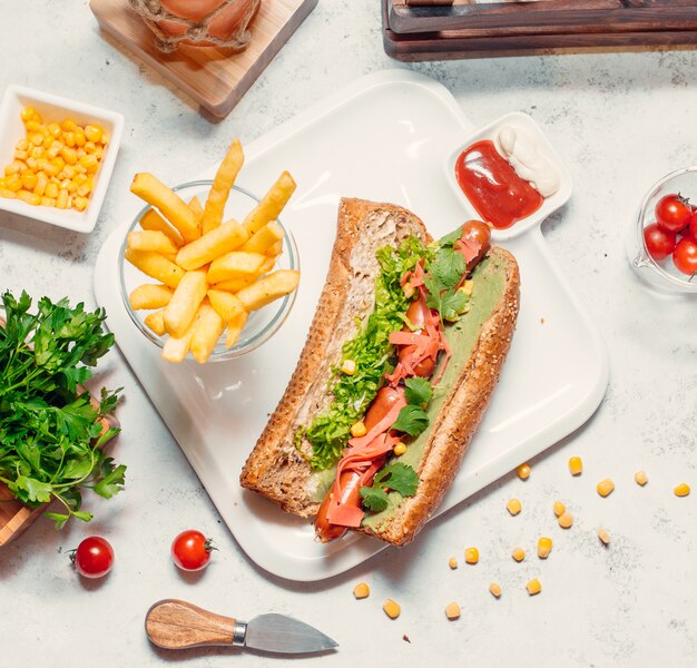 Emparedado de pan con hierbas y tomates y papas fritas alrededor.