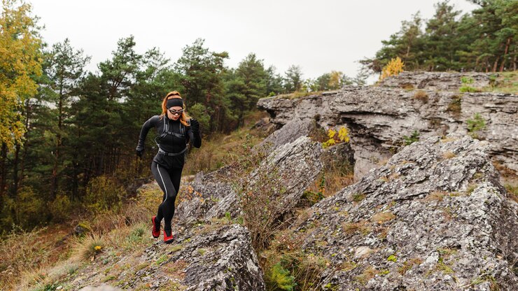 Foto gratuito emparejador deportivo femenino corriendo sobre piedras tiro largo