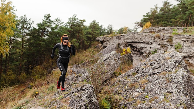 Emparejador deportivo femenino corriendo sobre piedras tiro largo