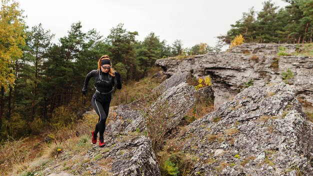 Emparejador deportivo femenino corriendo sobre piedras tiro largo