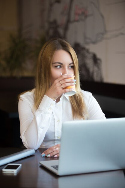 Empleada disfrutando de un café mientras trabaja